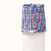 Blue pleated denim lampshade with a print of pink, red, and green flowers